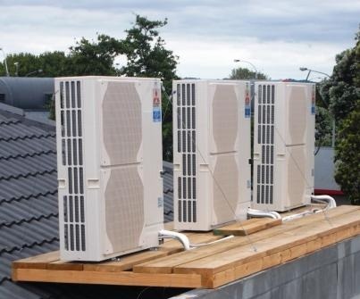Three outdoor condensing units mounted on a roof platform at Nomad Bar & Grill